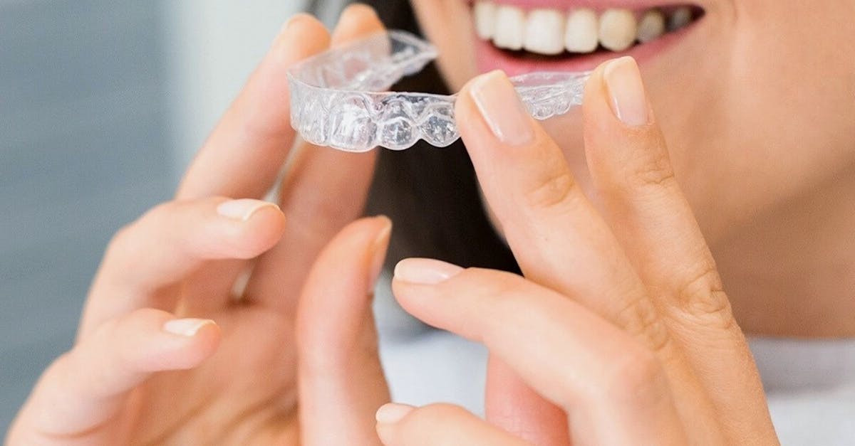 Aligners & Braces Smiling woman holding a clear dental aligner used for invisible teeth straightening