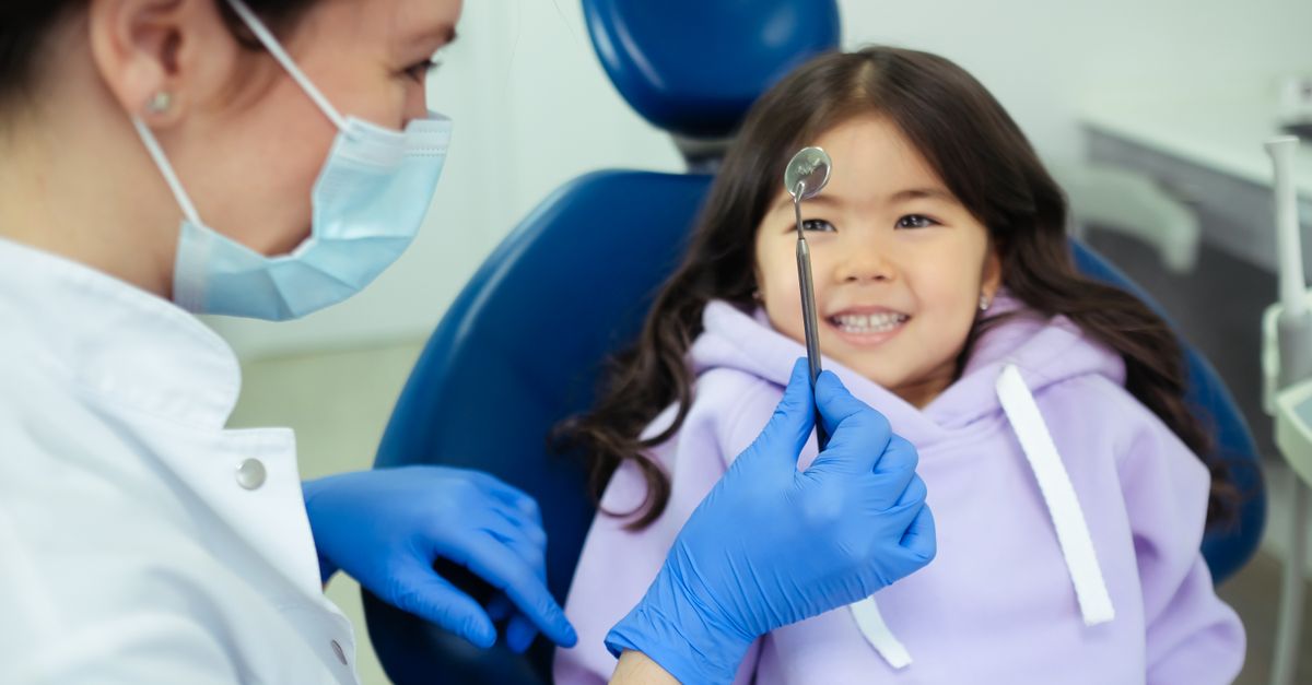 Paediatric Dentistry Friendly dentist gently checking a smiling child's teeth in a child-friendly clinic